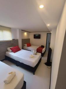 Habitación de hotel con 2 camas y TV de pantalla plana. en Hotel Orion, en Chinchiná