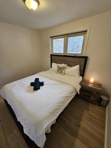 een slaapkamer met een groot wit bed met een hoed erop bij Games BBQ with a upgraded stay near kawartha in Lakefield