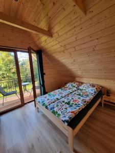 a bed in a wooden room with a large window at Chatka Przy Miedzy in Jabłonka
