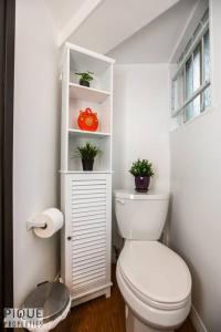 La salle de bains est pourvue de toilettes et d'une étagère avec des plantes. dans l'établissement Casa LeBlanc - Latin Vibes - Sleep 8 - Netflix - Long Term, à Edmonton