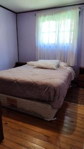 1 cama en un dormitorio con ventana en Casa o habitacion en carretera austral, en Puerto Montt