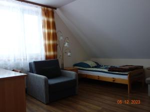 een slaapkamer met een bed, een stoel en een raam bij Dom Młodzieżowy w Polanie in Serednie Małe