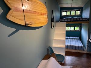 a room with two bunk beds and a surfboard on the wall at CASA DE CHICO - Tiny House in Guarda do Embaú