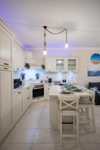 eine Küche mit weißen Schränken und einem Tisch mit Stühlen in der Unterkunft The Nautical Nook in Marsaxlokk