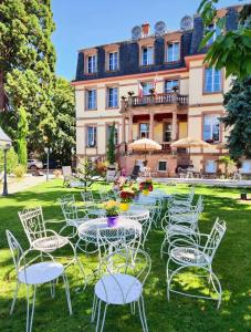 een groep tafels en stoelen voor een gebouw bij Hôtel Le Manoir in Barr