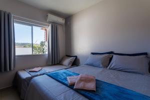 2 camas en una habitación con ventana en Curta Praia de Armação - Casa Orquídea, en Penha