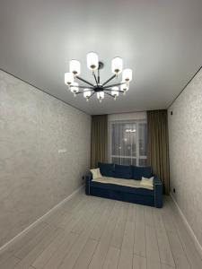 Habitación grande con cama azul y lámpara de araña. en Sharyn, en Kirovo