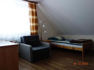 een slaapkamer met een bed, een stoel en een raam bij Dom Młodzieżowy w Polanie in Serednie Małe