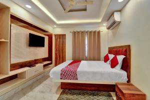 um quarto com uma cama e uma televisão de ecrã plano em OYO Flagship OXY QUEEN PALACE em Jamshedpur