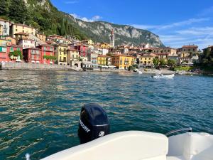 a boat in a body of water with a city at Il terrazzo sul Lago in Varenna