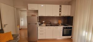 cocina con armarios blancos y nevera de acero inoxidable en Comfy apartment- Sunny balcony en Tirana