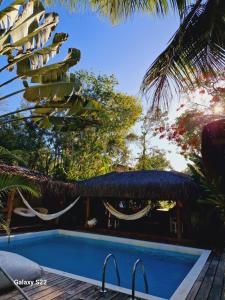 a resort with a swimming pool and a palm tree at Mini Casa com Jacuzzi e Piscina in Trancoso