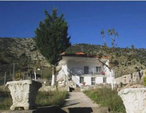 a large white house with a hill in the background at Mirto’s House in Tripótama