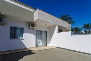 Casa blanca con 2 ventanas y una puerta en Curta Praia de Armação - Casa Orquídea, en Penha