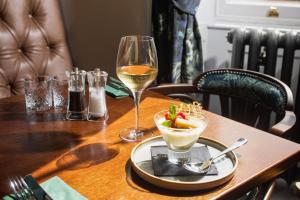 a table with a glass of white wine and a dessert at The Ullswater Inn- The Inn Collection Group in Glenridding
