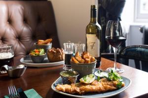 a table with a plate of food and a glass of wine at The Ullswater Inn- The Inn Collection Group in Glenridding