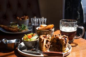 a table with a plate of food and a glass of beer at The Ullswater Inn- The Inn Collection Group in Glenridding