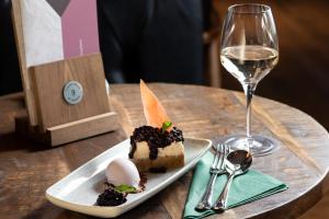 a piece of cake on a plate next to a glass of wine at The Ullswater Inn- The Inn Collection Group in Glenridding