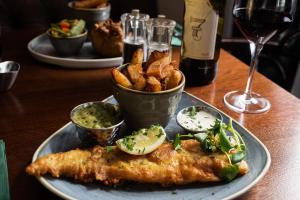 a plate of food with fish and fries on a table at The Ullswater Inn- The Inn Collection Group in Glenridding