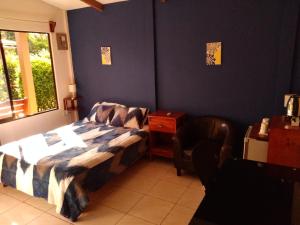 1 dormitorio con 1 cama, 1 silla y 1 ventana en Slow Travel Lodge, en Upala