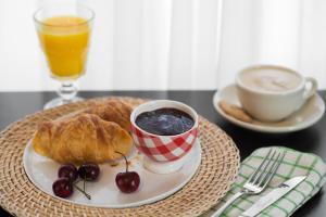 a plate with a croissant and a cup of coffee and cherries at Sun City Hotel in Tel Aviv