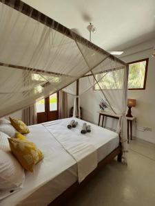 ein Schlafzimmer mit einem großen Bett mit Baldachin in der Unterkunft Swallow villa - French guest house in Ahangama