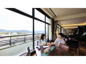 Due donne sedute a un tavolo in una stanza con vista di Ryokan Biyu no Yado - Vacation STAY 16236v a Yokokura