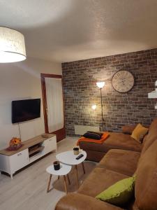 a living room with a couch and a clock on a brick wall at Descanso en el pirineo in Villanúa