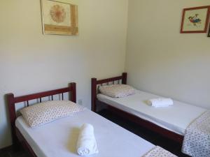 two twin beds in a room with white walls at Pousada Sino dos Ventos in São Sebastião do Rio Verde