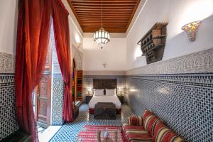 um quarto de hotel com uma cama e um sofá e um quarto em Riad La Perle De La Médina em Fez