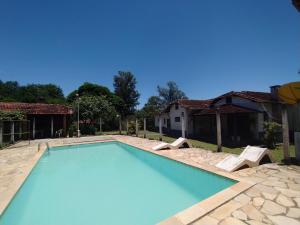 uma piscina com duas cadeiras e uma casa em Pousada Sino dos Ventos em São Sebastião do Rio Verde