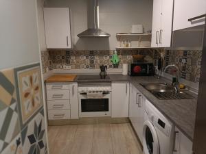 a small kitchen with white cabinets and a sink at La Azotea de Cristina in Seville