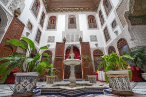 a courtyard with a fountain in a building with plants at Riad La Perle De La Médina in Fès