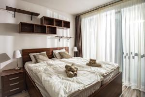 a bedroom with a large bed with two teddy bears on it at Forest Park Garden Apartment in Bratislava