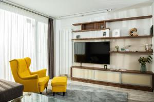 a living room with a television and a yellow chair at Forest Park Garden Apartment in Bratislava