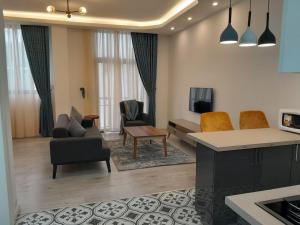 ein Wohnzimmer mit einem Sofa, Stühlen und einem TV in der Unterkunft Zemilo Hotel Apartment in Addis Abeba
