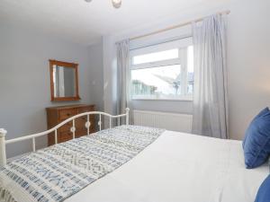 a bedroom with a white bed and a window at The Beach House in Pwllheli