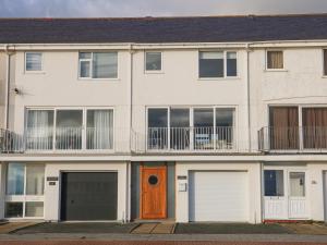 an apartment building with two garages and a wooden door at The Beach House in Pwllheli