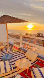 eine Gruppe von Stühlen und einem Sonnenschirm am Strand in der Unterkunft Surf Break Morocco in Imsouane