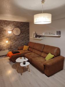 a living room with a brown couch and a brick wall at Descanso en el pirineo in Villanúa