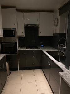 a kitchen with white cabinets and black appliances at A modern flat in Southeast London in London