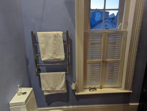a bathroom with a window and a toilet and towels at La Montagne Observatory in Cape Town