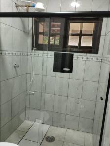 a shower with a glass door in a bathroom at Apê Aconchegante - 4 pessoas in Bertioga +18 photos