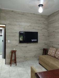 ein Wohnzimmer mit einem Sofa und einem TV an der Wand in der Unterkunft Ap Aconchegante - 4 pessoas in Bertioga