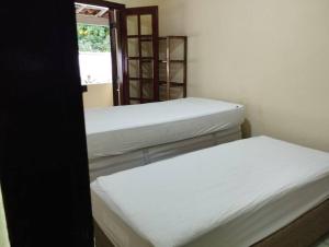 a room with three beds and a window at Apê Aconchegante - 4 pessoas in Bertioga