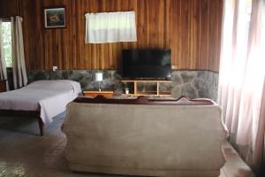 a bedroom with a bed and a flat screen tv at El Bosque Lodging in Monteverde Costa Rica