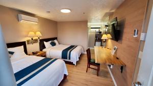 a hotel room with two beds and a desk at Harbour Light Motel in Nanaimo