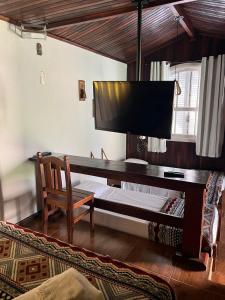 a computer desk with a flat screen tv on a wall at Village Colonial Pousada in Penedo