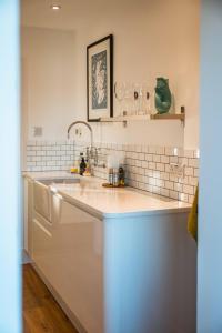 a white kitchen with a sink and a counter at Kinkell Cottage in Dingwall