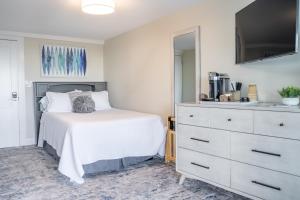 a bedroom with a white bed and a dresser at 935 Ocean, a Beachside Inn in Hampton